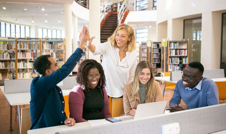 Vrolijke multiculturele studenten die high five geven aan de leraar