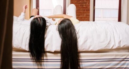 Vrouw liggend op bed met haar handen voor haar gezicht