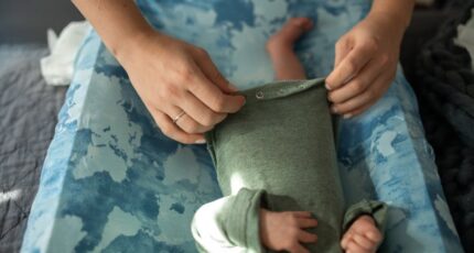 Een persoon kleedt een baby aan.
