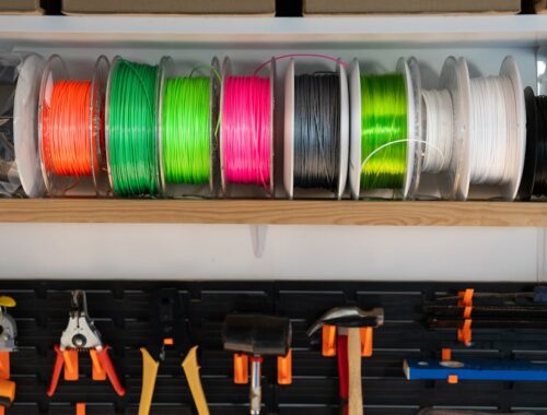 Kleurrijke 3D-printfilament op spoelen, verspreid in verschillende tinten.