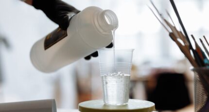 Persoon giet epoxyhars in een plastic bekertje.