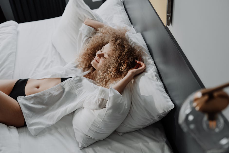 Vrouw in een witte jurk liggend op een bed, met een serene uitdrukking.