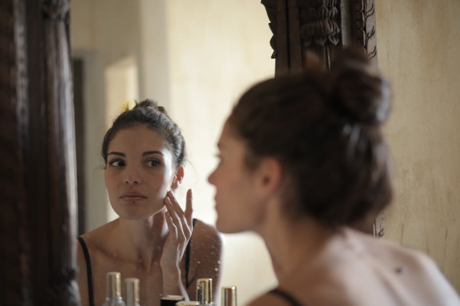 een foto van een vrouw die geen make-up draagt en haar huid controleert in de spiegel