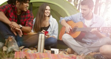 een man speelt gitaar bij een tent op festivalterrein