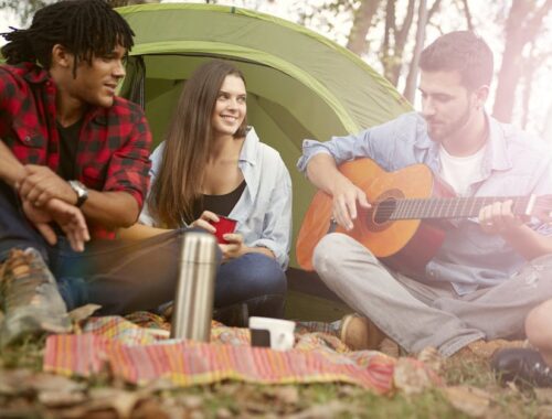 een man speelt gitaar bij een tent op festivalterrein