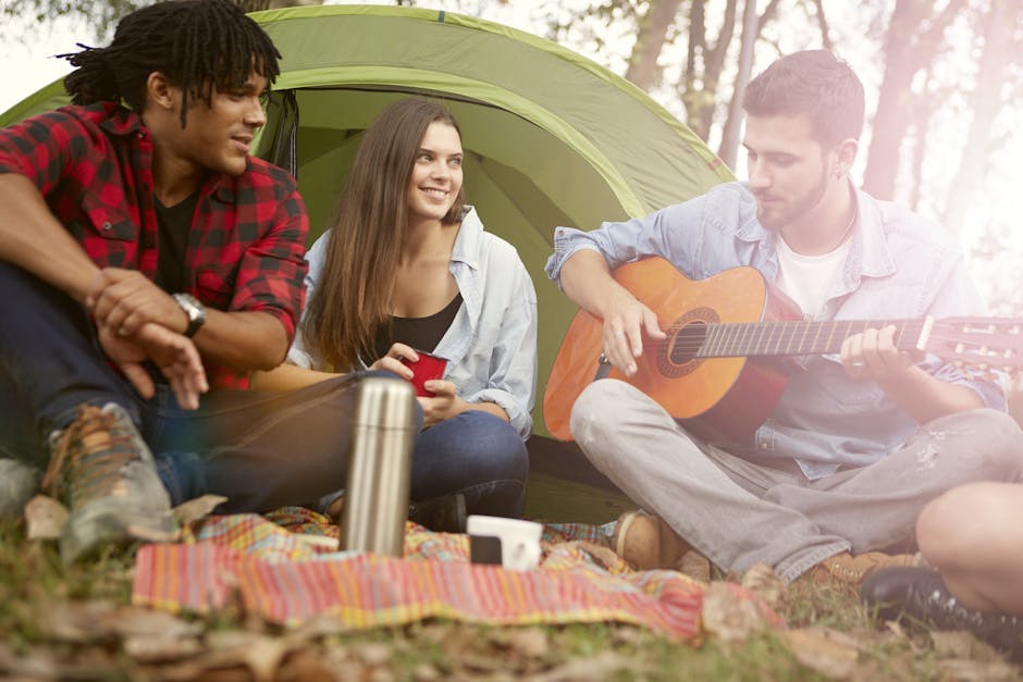 een man speelt gitaar bij een tent op festivalterrein