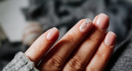 Detailopname van een vrouw zonder gezicht die haar manicure met nagelkunst toont.